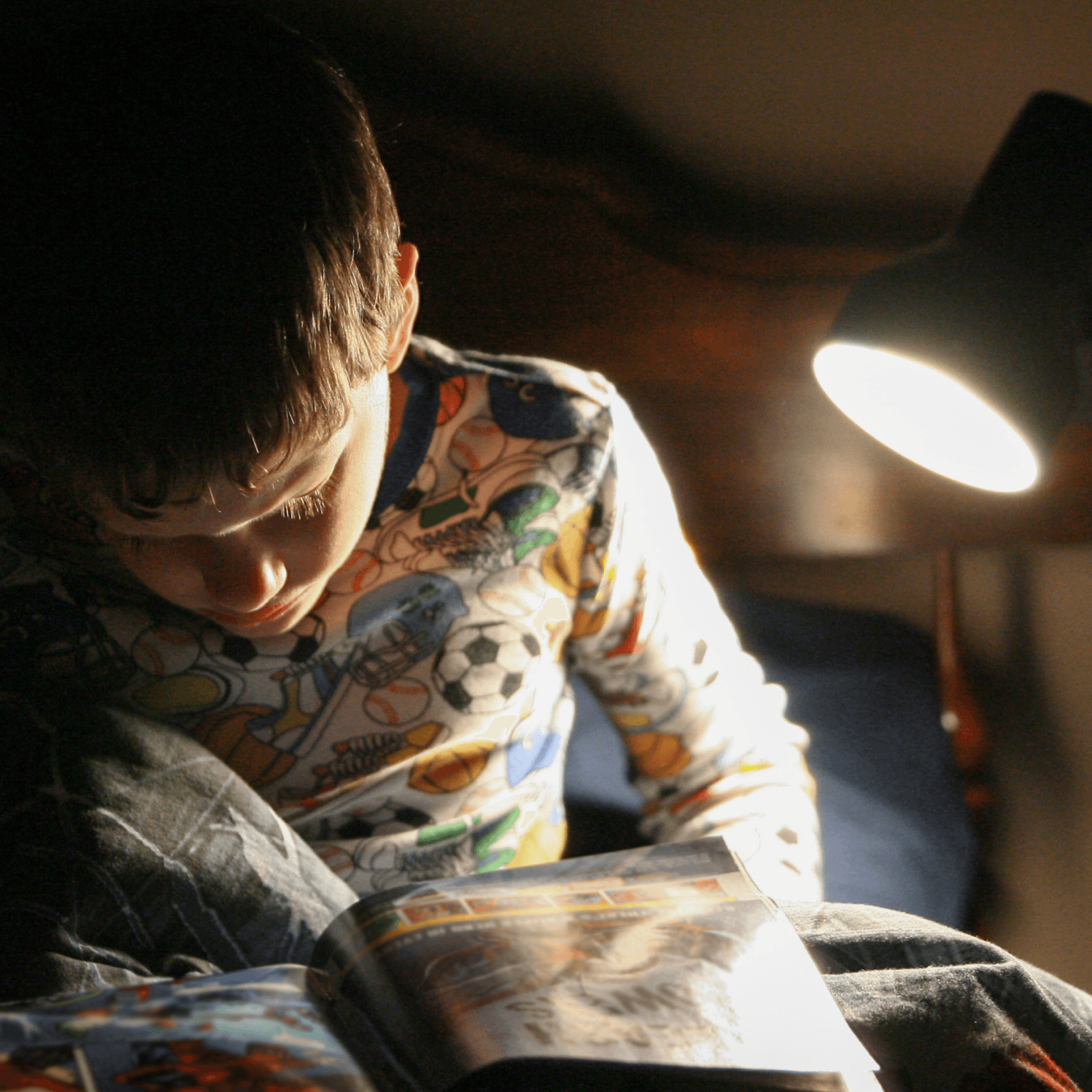 A child reading a book under a lamp