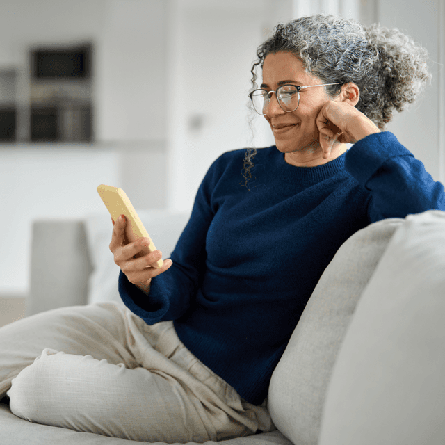 A woman looking at her phone sitting on a couch